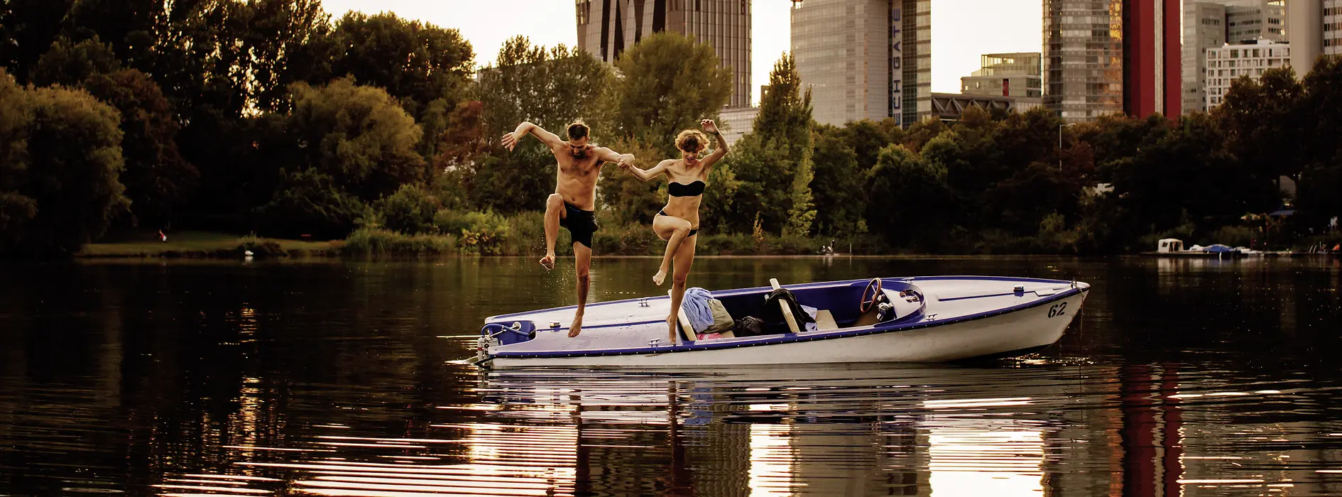 A man and a woman jump from a boat into the water