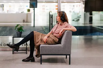 Frau mit einem Kopfhörer schaut sich etwas auf einem Fernseher an