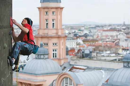 Mann klettert am Flakturm vor Wien-Panorama
