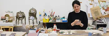 Onka Allmayer-Beck modeling clay at the table in her studio